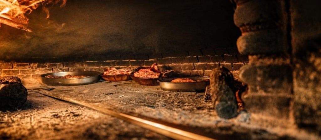 Cazuelas de asado dentro del horno de leña con brasas