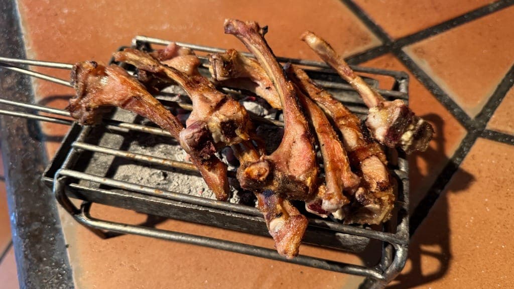 Chuletillas de lechazo a la brasa sobre parrilla con ascuas de leña