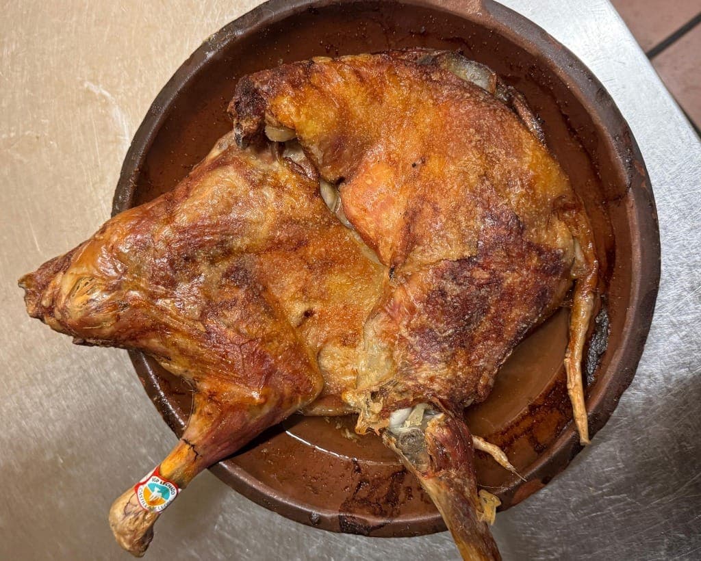 Lechazo asado IGP Castilla y León en cazuela de barro tradicional recién salido del horno