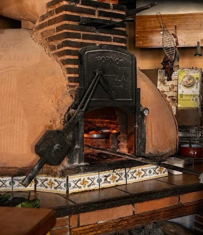 Pala de horno introduciendo la cazuela de asado en el horno tradicional