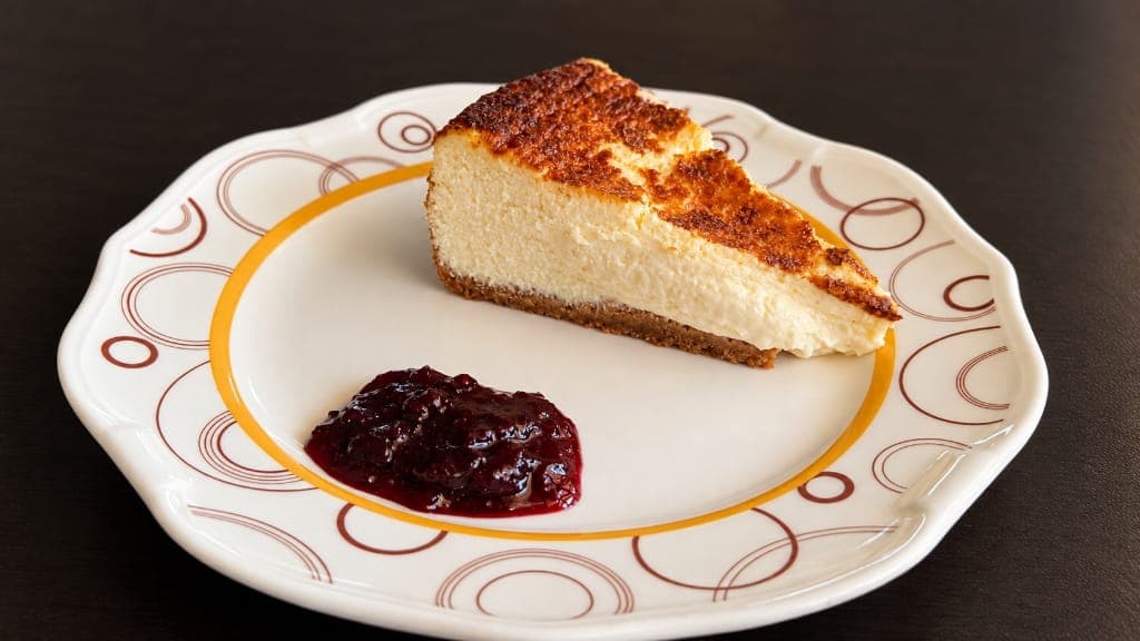 Porción de tarta de queso casera horneada con mermelada de frutos rojos