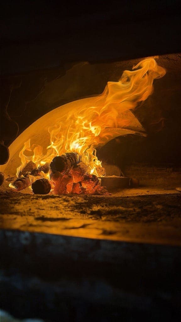 Fuego y brasas de leña en el horno tradicional de Asador La Antigua
